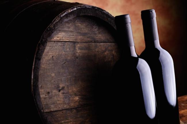 Wine Bottles next to a wooden barrel