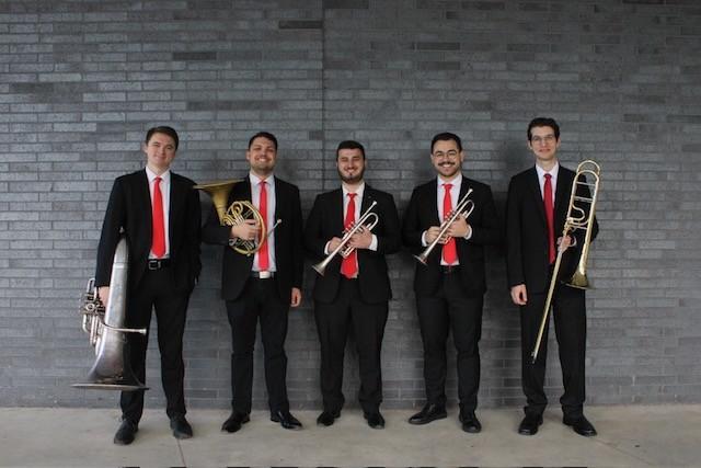 The Bulldog Brass Society standing in front of a gray brick wall