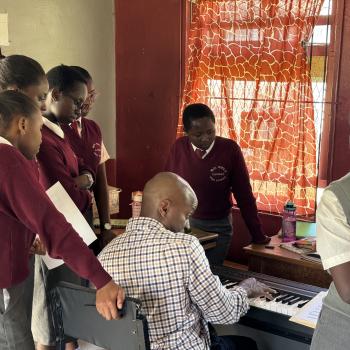 Greg Satterthwaite demonstrating on a keyboard for a group of students at the Moi Girls School.